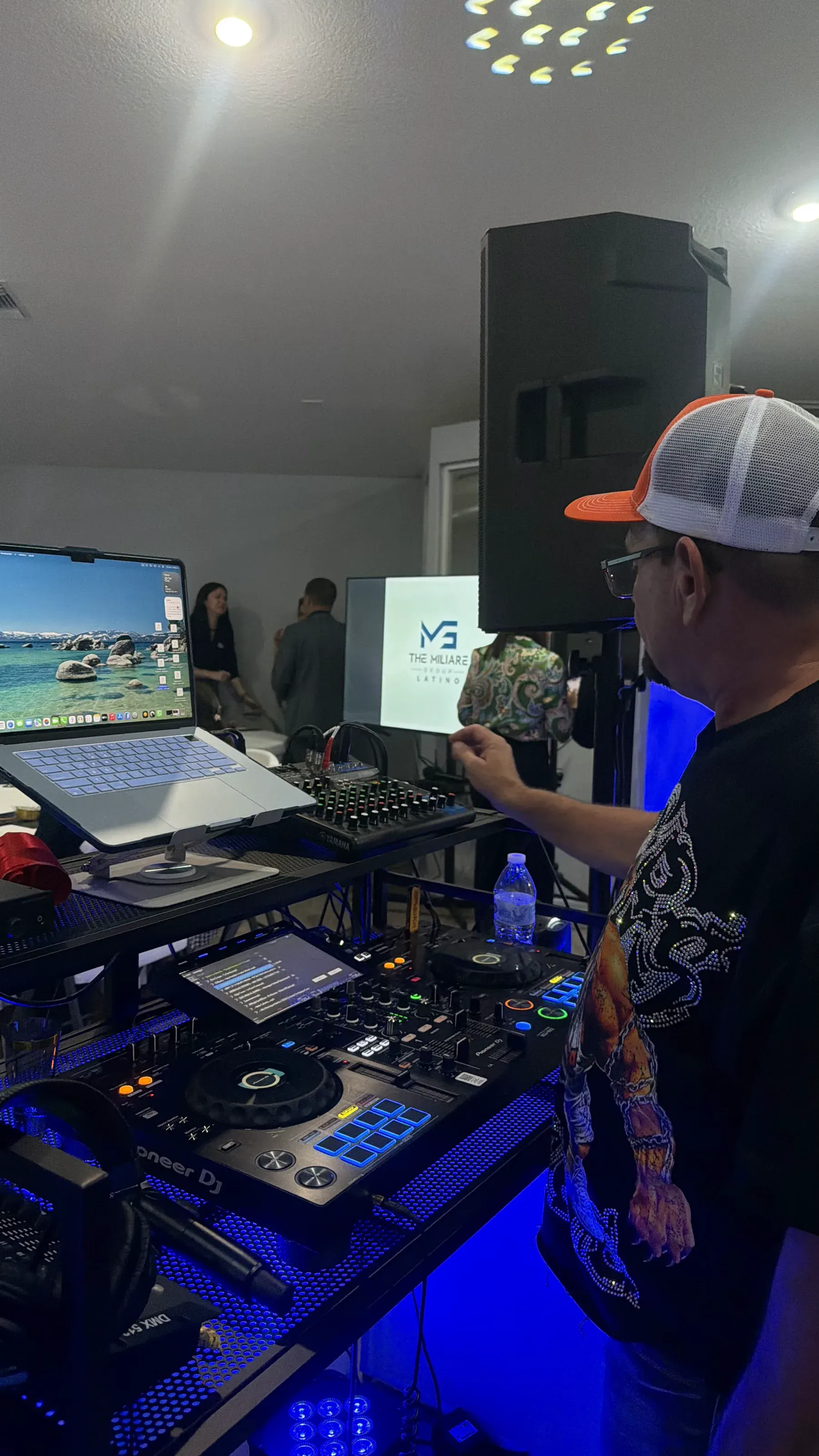 A Cepero DJ booth lit in blue, with the Pioneer controller and a powered speaker